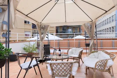 a patio with tables and chairs and an umbrella at ApartEasy - Private terrace, 3 bedrooms, Eixample in Barcelona