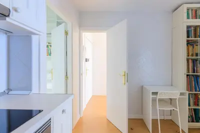 a white kitchen with a desk and a book shelf at ApartEasy - Private terrace, 3 bedrooms, Eixample in Barcelona
