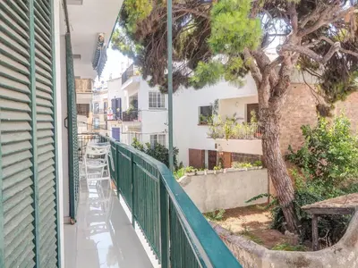 a balcony with a green fence and a tree at Aolani Apartment by Hello Homes Sitges in Sitges