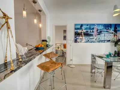 a kitchen with a bar and a table and chairs at Aolani Apartment by Hello Homes Sitges in Sitges