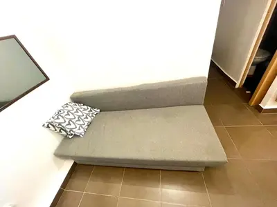 a couch with a pillow sitting on top of a floor at B3 planta baja al lado del metro in Barcelona