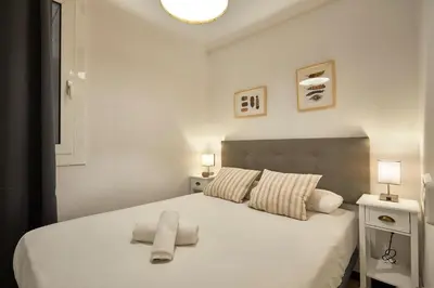 a bedroom with a white bed with two towels on it at BBarcelona Sagrada Familia Garden Apartment in Barcelona