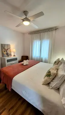 a bedroom with a large white bed with a ceiling fan at Vila Sitges, big house with pool in Sitges