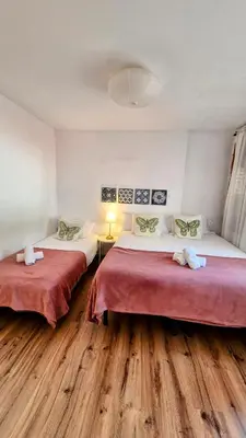 two beds in a room with wooden floors at Vila Sitges, big house with pool in Sitges