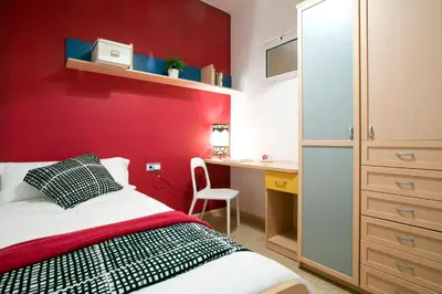 a bedroom with a red wall with a bed and a desk at Rainbow in Barcelona