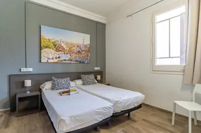 a bedroom with two beds and a painting on the wall at AB Marina Apartments in Barcelona