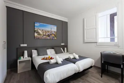a bedroom with a large bed and a table at AB Marina Apartments in Barcelona