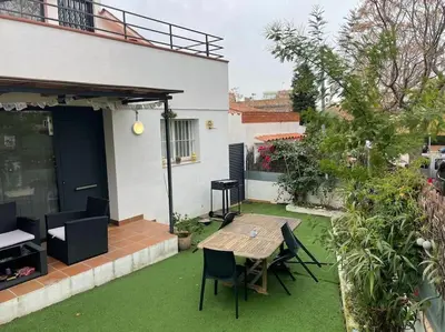 a patio with a wooden table and chairs on grass at House in Sant Cugat, 25 Mins to Barcelona center in Sant Cugat del Vallès