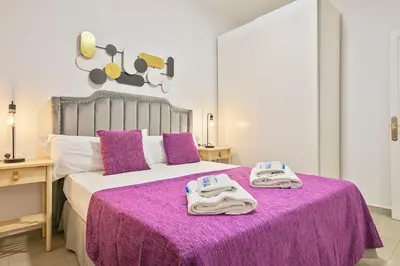a bedroom with a purple bed with towels on it at Alcam Baro 22 in Barcelona