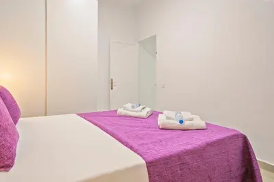 a white bed with two towels on a purple blanket at Alcam Baro 22 in Barcelona