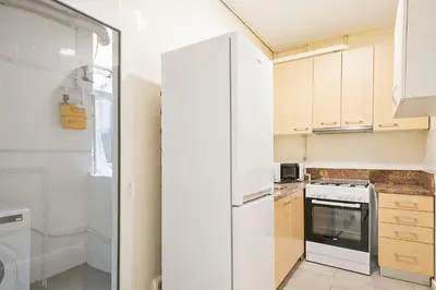 a kitchen with white cabinets and a refrigerator at Alcam Baro 22 in Barcelona