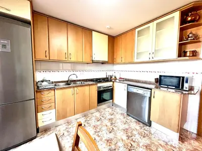 an empty kitchen with wooden cabinets and appliances at Amplio Apartamento, 5 camas in Sant Esteve Sesrovires