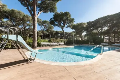 a swimming pool with a slide and a swimming pool at Lets Holidays Castelldefels Diagonal Orient in Castelldefels