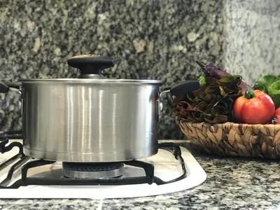 a pot on a stove with a basket of vegetables at Lets Holidays Castelldefels Diagonal Orient in Castelldefels