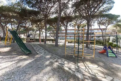 a park with a playground with swings and trees at Lets Holidays Castelldefels Diagonal Orient in Castelldefels