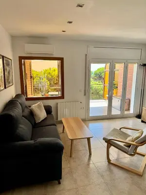 a living room with a black couch and a table at Apartment in front of the beach in Castelldefels