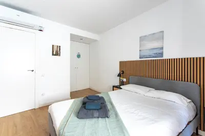 a bedroom with a large bed with a wooden headboard at StayCampNou 3BR With Balcony in Hospitalet de Llobregat