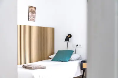 a bedroom with a bed with a blue pillow on it at StayCampNou 3BR With Balcony in Hospitalet de Llobregat