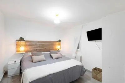 a white bedroom with a large bed and a flat screen tv at Apartamento Luna in Montgat