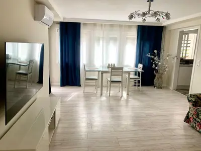 a living room with a dining room table and blue curtains at Puig comfort in Calella