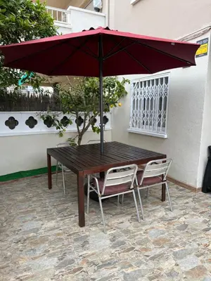 a wooden table and two chairs under an umbrella at Apartamento Villa Caracol in Cunit