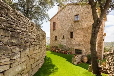 an old stone building with a tree next to it at Masía espectacular cerca de Barcelona in Granera