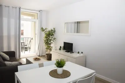 a white living room with a table and a tv at Sant Jordi Apartments Sagrada Familia in Barcelona