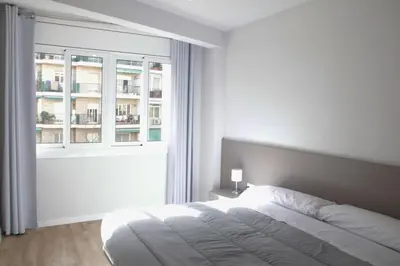 a white bedroom with a bed and a window at Sant Jordi Apartments Sagrada Familia in Barcelona