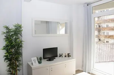 a white living room with a tv and a window at Sant Jordi Apartments Sagrada Familia in Barcelona