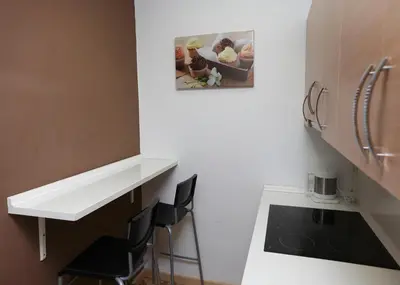 a kitchen with a white counter and two black chairs at Apartamentos Olivier in Barcelona