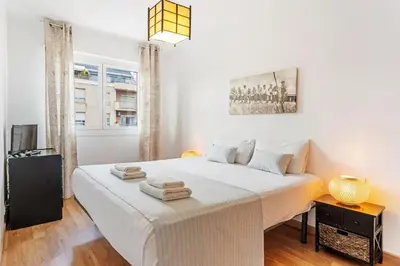 a white bedroom with a large bed with towels on it at Sunny 3BR for 4 Iconic Terrace Views in Barcelona