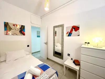 a white bedroom with a bed and a mirror at Apartment Sagrera in Barcelona