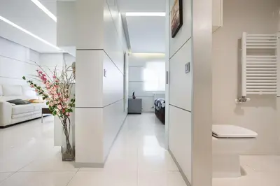 a hallway with white walls and a vase of flowers at Apartamento en la playa de Castelldefels ( Barcelona) in Castelldefels