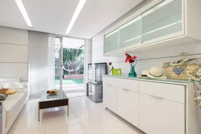 a kitchen with white cabinets and a living room at Apartamento en la playa de Castelldefels ( Barcelona) in Castelldefels