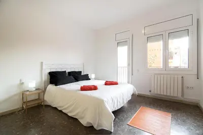 a white bedroom with a large white bed with red pillows at Holiday home Splendid Park Güell in Barcelona