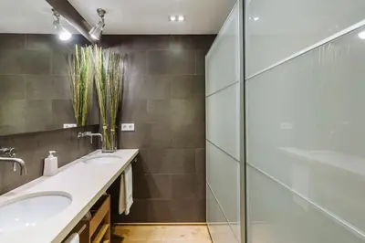 a bathroom with two sinks and a glass shower at ArtlifeBCN Fira Apartment in Barcelona