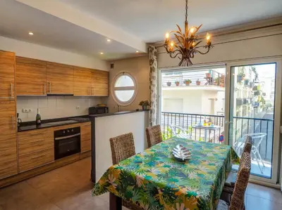 a kitchen and dining room with a table and a kitchen and a balcony at Zafiro Apartment by Hello Homes Sitges in Sitges