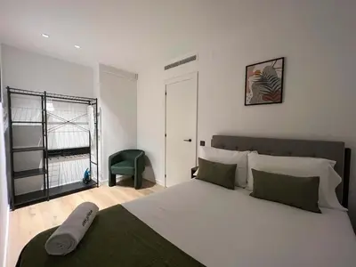a bedroom with a large bed and a green chair at Stay U-nique Apartments Putxet in Barcelona