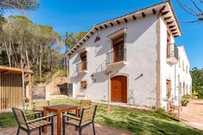 an exterior view of a house with two chairs and a table at La Terraza - Großzügiges Appartment in Katalanischer Masia in Sant Iscle de Vallalta