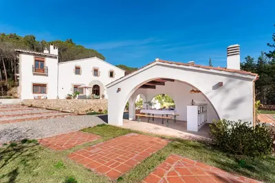 an external view of a white house with an archway at La Terraza - Großzügiges Appartment in Katalanischer Masia in Sant Iscle de Vallalta