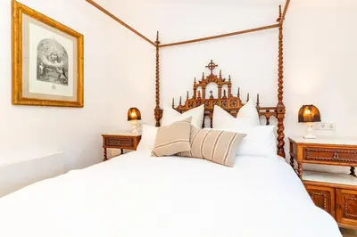 a bedroom with a large white bed with a wooden headboard at El Huerto - Großzügiges Appartment in Katalanischer Masia in Sant Iscle de Vallalta