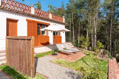 a white house with an umbrella and a bench at Gallinero - Familienfreundliches Appartment in Katalanischer Masia in Sant Iscle de Vallalta