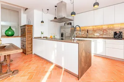 a kitchen with white cabinets and a wooden counter top at Gallinero - Familienfreundliches Appartment in Katalanischer Masia in Sant Iscle de Vallalta