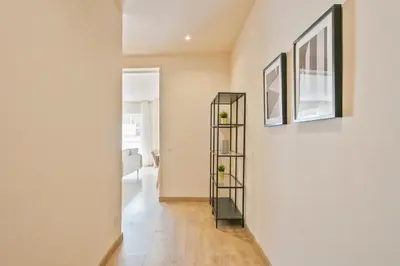 a hallway with a white wall and a black shelf at Alcam Galileu P in Barcelona