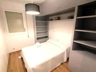 a small bedroom with a white bed and shelves at Corcega - Sagrada Familia in Barcelona