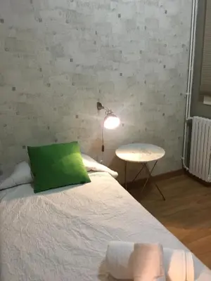 a bedroom with a bed with a green pillow and a table at Corcega - Sagrada Familia in Barcelona