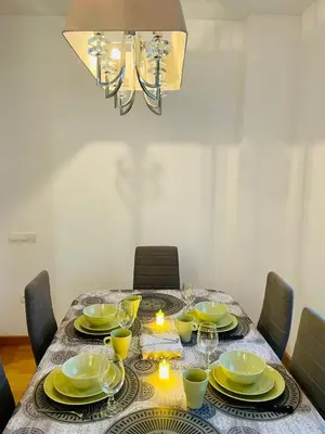 a dining room table with yellow dishes and a chandelier at Luxe Forum Beach Terrace in Sant Adria de Besos