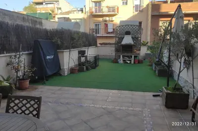 a backyard with a green lawn in front of a building at Precioso apartamento con magnífico patio. in Sant Feliu de Llobregat