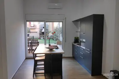 a kitchen with a wooden table and a large window at Precioso apartamento con magnífico patio. in Sant Feliu de Llobregat