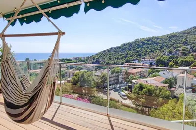 a hammock on a balcony with a view of a city at Design Apartment with Sea View in Castelldefels